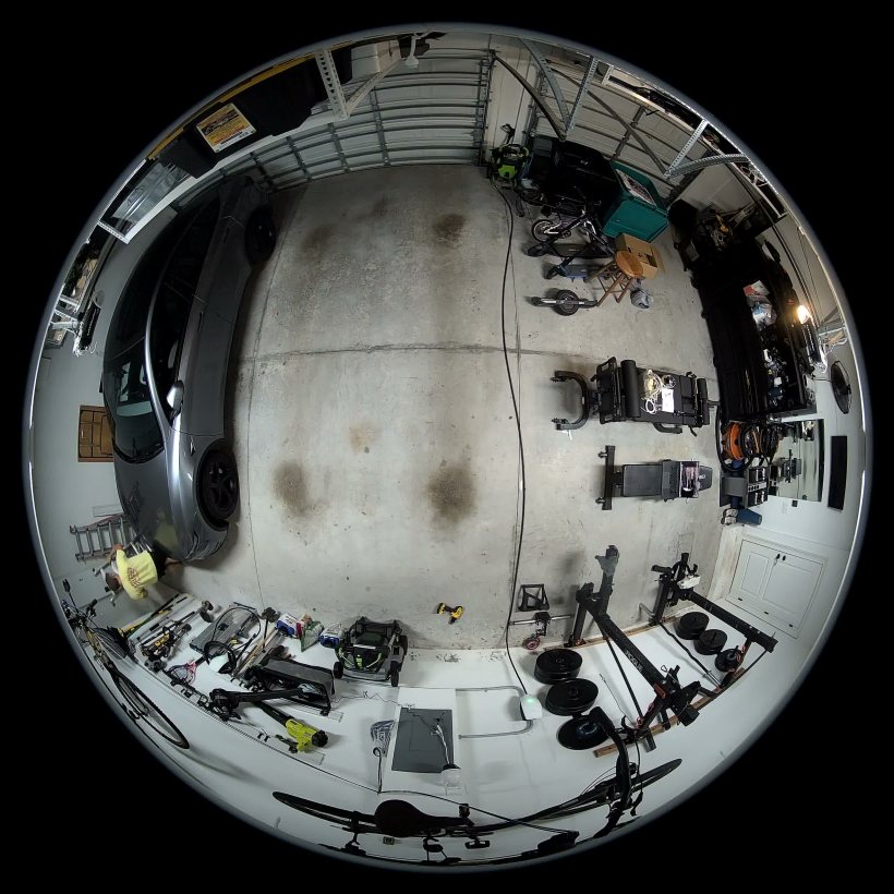 Raw circular fisheye frame looking down at the garage, every straight line bent into an arc
